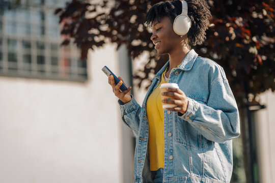 Black woman enjoying coffee and music outdoors