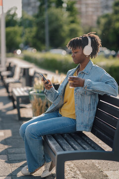 Woman relaxing on park bench listening to music