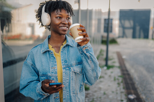 African american woman enjoying music and coffee in urban setting