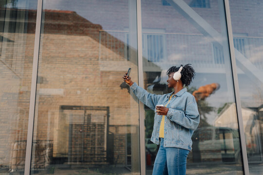 Black woman taking selfie with headphones and coffee