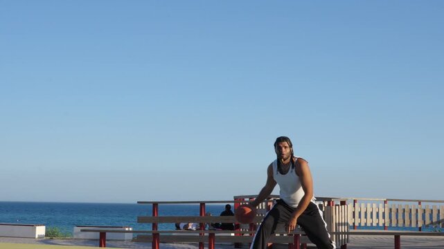 Streetball player making a shot on an outdoor court by the sea