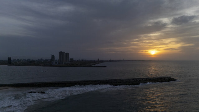 Aerial view of Tarkwa Bay Beach at sunset with a breakwater extending into the Atlantic Ocean and the Lagos city skyline in the distance, Lagos, Lagos, Nigeria.