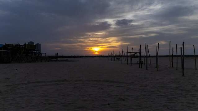 Aerial view of Tarkwa Bay Beach at sunset with wooden poles lining the sandy shore under a dramatic cloudy sky in Lagos, Lagos, Nigeria.