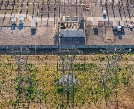 Aerial view of high voltage transmission pylons, power transformer, and electrical substation infrastructure connecting the electricity grid in Saulce-sur-Rhone, Auvergne-Rhone-Alpes, France.