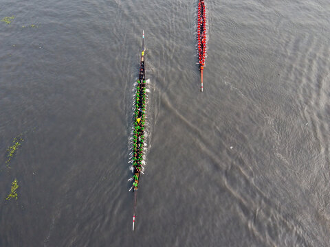 Aerial view of a traditional boat race with rowers in green and red uniforms paddling long narrow boats on the river in Gopalganj, Dhaka Division, Bangladesh.