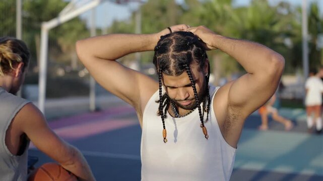 Basketball player tying braided hair on outdoor court