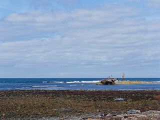 The disintegrating wreck of the Sovereign Fishing Boat on the rocks at Cairnbulg Point Navigation Beacon in Fraserburgh Bay at Low Tide. © Julian