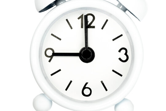 Close-up of white analog alarm clock showing nine o'clock on white background