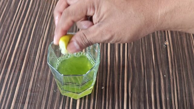 Squeezing Fresh Green Lime Juice into Glass Cup