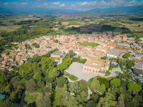 Aerial view of the historic Castell de Peralada surrounded by lush gardens, trees, and the charming town rooftops in Peralada, Catalonia, Spain.