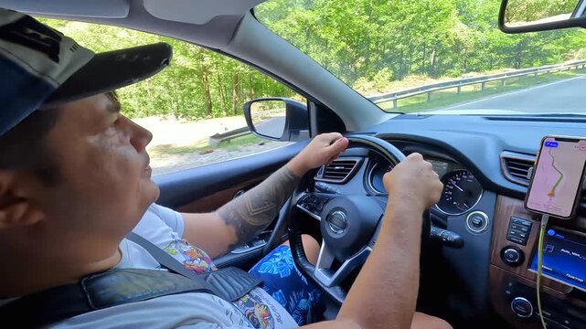 Driver follows mountain route, over-shoulder view inside a car with phone navigation on the road to Svaneti, Georgia, illustrating GPS guidance, independent travel and regional trip planning