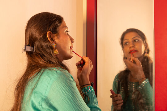Woman applying lipstick in front of a mirror