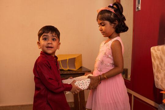 Young siblings exchanging a gift in a festive setting