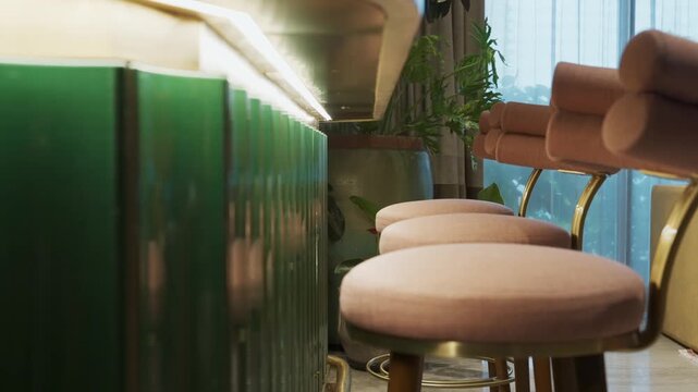 Modern luxury lounge interior featuring pink velvet stools and green ribbed bar counter.