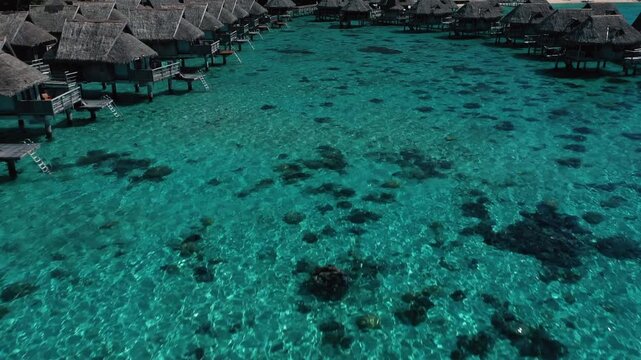 Aerial view of luxury overwater bungalows in tropical turquoise lagoon of Bora Bora.