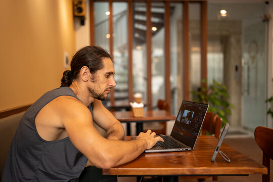 Man working remote on laptop editing video in cafe