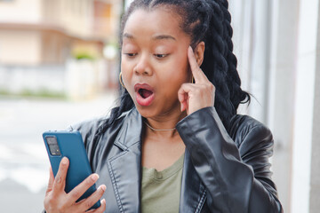 woman on the street making a face of surprise or amazement when she reads a message on her mobile...