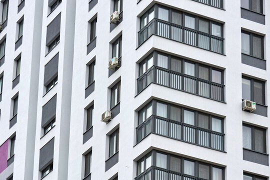 Modern residential building facade with glass balconies and red accents