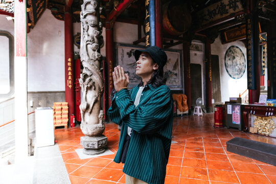 Young man praying in an ancient taiwanese temple