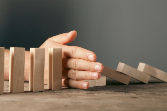 Businessman hand stopping domino effect. Risk management and strategy concept