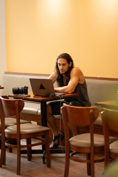 Male digital nomad working on laptop in cafe