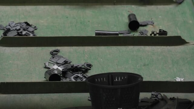 Discarded plastic components riding a green cleated conveyor into shredding at a Recycling Factory