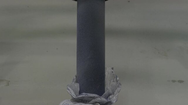 Woven sack collar cinched onto a discharge chute over a mound of granulate at a Recycling Factory