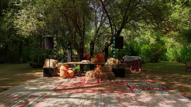 Rustic garden dance floor laid with kilim carpets straw bales and clay pots in dappled shade