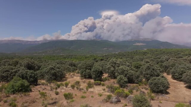 Ascending drone view over the Ti&eacute;tar Valley showing a massive pyrocumulus cloud rising above the northern side of the Central Mountain Range, generated by an intense wildfire.