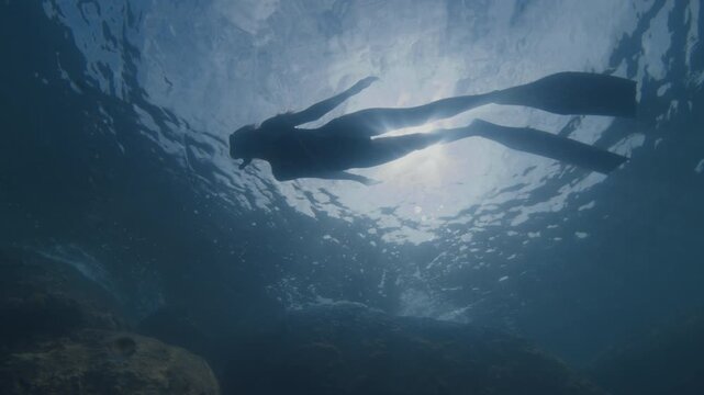 Young slim woman swims underwater, freediving and snorkeling in the sea near the coral reef near the island of Ilha Grande in Brazil
