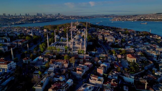 Sultan Ahmed Mosque, known as the Blue Mosque, standing prominently against a clear sky with the Istanbul cityscape and Bosphorus. Nice aerial view wide orbit drone panorama overview