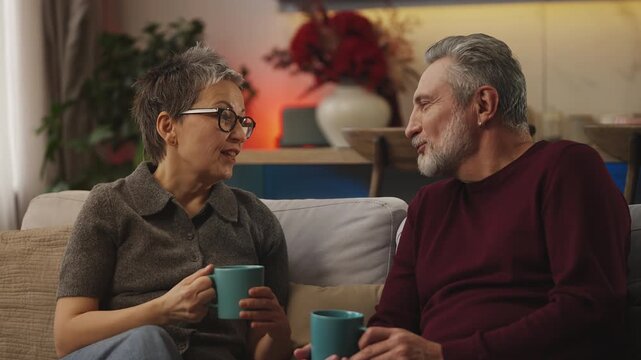 Middle-aged woman and husband discuss news and laugh while drinking tea