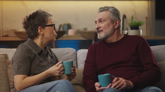 Mature woman and husband chat over tea at home, enjoying time together