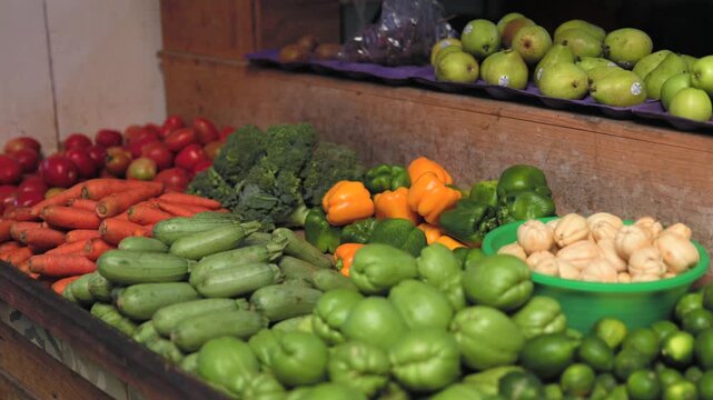 Fresh Mexican market vegetables including chayote, zucchini, carrots, broccoli, bell peppers, limes and tomatoes displayed at a traditional produce stall. Close up shot.