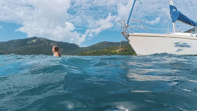 Young woman jumps into the sea from the sailing boat