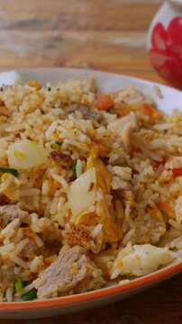 Thai Pork Fried Rice with Cucumber Slices and Lime on Rustic Wooden Table, Homestyle Asian Comfort Food