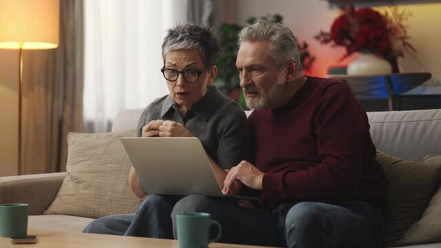 Mature woman and husband read bad news email on laptop about failed trip