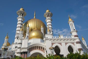 Obraz premium Majestic Ubudiah Mosque architecture featuring ornate white walls and large golden domes against a blue sky golden dome white building Islamic architecture religious building place of worship
