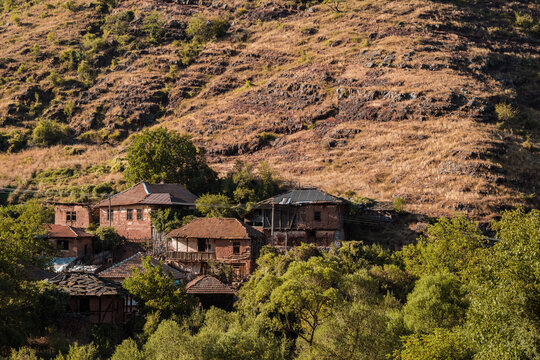Traditional old houses made of mud, earth, and wood under a steep rocky hill in Topli Do village, showcasing authentic vernacular architecture at Stara Planina in Serbia 13.08.2026