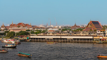Obraz premium Cityscape view of riverside temples and boats during daytime in Bangkok, Thailand