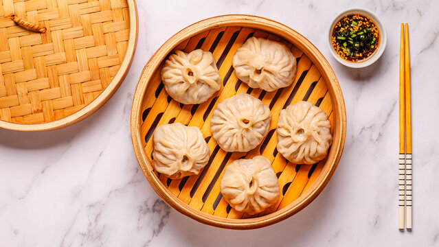 Steaming basket filled with dumplings on a marble table