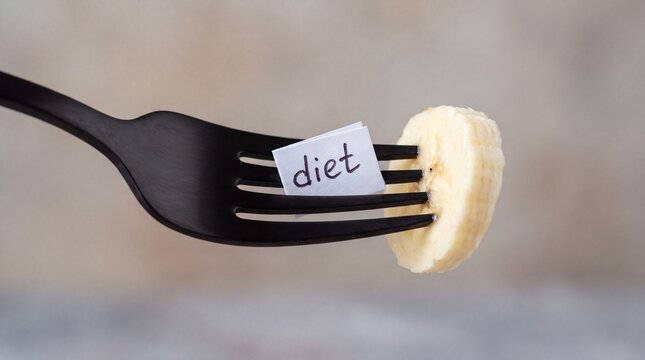 Banana slice on fork with word diet written on paper.