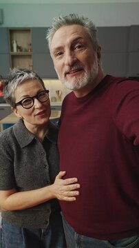 Smiling middle-aged couple make video call on phone, talking to their children