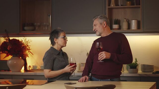 Middle-aged man and wife talk while drinking wine, enjoying bonding time