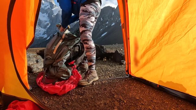 Mountaineer packing gear from tent view at alpine campsite in Svaneti, Georgia, outdoor scene for expedition preparation, backpacking equipment ads, trekking logistics, and mountain travel promotion