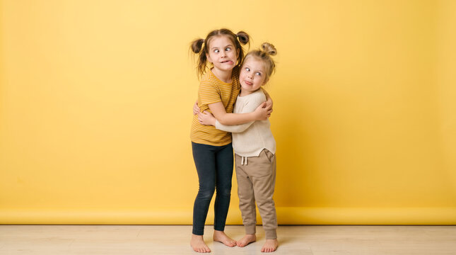 Two young sisters hugging and making goofy expressions with crossed eyes and silly faces