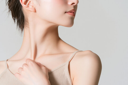 首元に手を添える若い日本人女性、デコルテと鎖骨の美しさを強調した美容・ボディケアイメージ