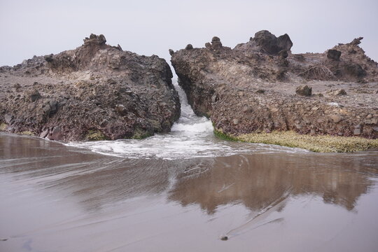 Sea waves emerge from the crevices of the rocks.