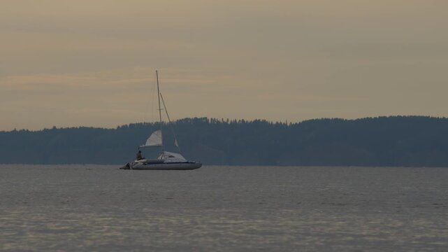 Sailing boat moves on the lake with during sunset