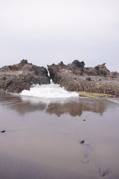 Sea waves emerge from the crevices of the rocks.